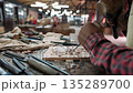 Close up of a carpenter using a chisel and mallet to carefully carve an intricate design into a wooden plank in a workshop, Siem Reap, Cambodia. 135289700