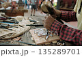 Close up of a craftsman hands carving intricate patterns on a wooden board. Traditional art of woodcarving in a workshop, Siem Reap, Cambodia. 135289701