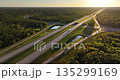 Aerial view of rural freeway junction with fast moving cars and trucks at sunset. Key part of American transportation infrastructure 135299169