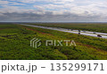 Aerial view of Florida highway slicing through natural wetland terrain with vehicles moving under a blue sky. 135299171