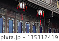 Two lanterns hang outside a building with intricate carvings and traditional Chinese architectural details. 135312419