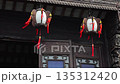 Two lanterns hang outside a building with intricate carvings and traditional Chinese architectural details. 135312420