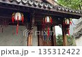 Three lanterns hang outside a building with intricate carvings and traditional Chinese architectural details. 135312422