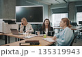 Team members discuss project updates and share ideas in a modern office space during a work meeting in the afternoon 135319943