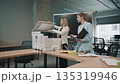 Office team collaborates at workplace around copier during busy work hours 135319946