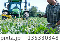 Farmer Spraying Crop Field with Tractor in Background 135330348