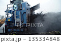 An industrial conveyor system aerator recycles organic waste using rising steam inside a waste processing plant. Depicts recycling technology and environmental engineering. This is an aerobic process 135334848