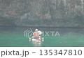 Man fishing, sea, raft, smoking e-cigarette on a sunny day in clear water near a rocky cliff 135347810