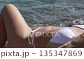 Bikini beach woman relaxes summertime sunbathing waves coastline holiday destination vacation on shore 135347869