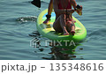 Paddleboard bikini woman relaxing on green paddleboard while man paddles on summer sea 135348616