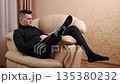 Injured leg, Reading book, Indoor reading. Person with prosthetic leg relaxes on couch with good book. 135380232