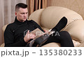 Book enjoyment, Prosthetic leg, Favorite book. Man with prosthetic limb unwinds on couch with book. 135380233