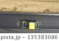 Aerial shot of slowly driving roller laying new asphalt layer. Top view to special machinery making road in countryside area. Drone tracking compactor constructing highway. Roadway repair. Top view 135383086