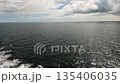 Open sea horizon with calm dark water and distant coastline under cloudy sky 135406035