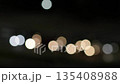 Abstract bokeh light background with blurred glowing circular shapes against dark night sky creating festive atmosphere and luminous effect 135408988