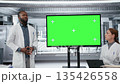 Chroma key display used by professor mentoring researchers during workshop in lab. African american man using isolated screen to present clinical trials breakthroughs to students, camera B 135426558