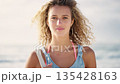 Face, woman and calm with curly hair at beach, summer travel and vacation, holiday or sunshine in Miami Florida. Portrait, gen z and young female relax at sea, wind and ocean for freedom and wellness 135428163