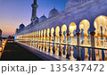 The Sheikh Zayed Grand Mosque is illuminated against blue twilight sky, showcasing its white marble domes and reflective pools in Abu Dhabi, UAE 135437472