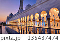 The Sheikh Zayed Grand Mosque is illuminated against blue twilight sky, showcasing its white marble domes and reflective pools in Abu Dhabi, UAE 135437474