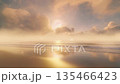 Golden sunrise over serene beach with foggy horizon 135466423