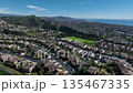 Aerial view over San Juan Capistrano, California, featuring the historic mission, library, sports courts, and an Amtrak train pulling into the downtown station. 135467335