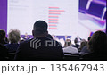 Conference audience watching analytical presentation rows of seated professionals dim auditorium 135467943