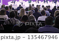 Formal conference setting with engaged professionals and stage lighting, Attentive audience of 135467946