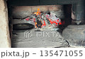a frying pan in a russian stove next to coals and burning firewood. a cast iron pot stands on the hearth. close-up. a frying pan in a russian stove next to coals and burning firewood. a cast iron pot stands on the hearth. close-up. 135471055