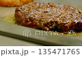 Hamburger patty sizzles fiercely on pan and releases savory aroma 135471765