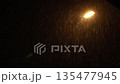 Rain drops hit the street lamp, the light illuminates the water close-up 135477945