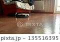 A robot vacuum cleaner cleans the floor in the apartment. 135516395