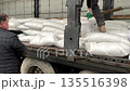 Workers unload white bags from a truck. Men discovered a batch of drugs in white bags in a truck.v 135516398