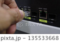 Hand plugging an Ethernet cable into a network switch port 135533668