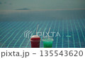 Two colorful cold drinks with straws placed on infinity pool edge, refreshing summer beverages against blurred water background with calm resort atmosphere and wide copy space 135543620