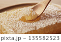 Scooping honey from comb honey with a wooden spoon 135582523