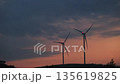 Tall windmills turn steadily in breeze generating electricity 135619825