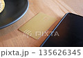 Gold card rests beside a smartphone on a wooden table 135626345