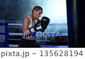 Slow motion, woman fighter beats a punching bag, hard training day in the boxing gym, fighter trains his punches, strength fit body. 135628194