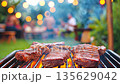Grilling steaks with smoky flavors on backyard party setting 135629042