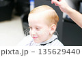 Little boy getting a stylish haircut at the barbershop 135629440