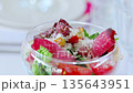 Glass bowl containing colorful salad with smoky sliced meat, ripe tomatoes, crisp lettuce, garnished with shredded cheese, presenting vibrant dining experience 135643951