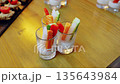 Colorful raw vegetable stickscarrots, cucumber, bell peppers, daikon radisharranged beside creamy dip in small glasses on rustic wooden surface, presenting nutritious snack option 135643984