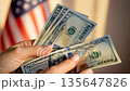 Woman counts us dollar money bills close up with american flag background. Financial money concept fits veterans day budget or independence day economy. Holding cash money flow. 135647826