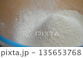 Flour falls from sieve into bowl below 135653768