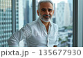 Middle-aged Middle Eastern HR manager standing confidently with a cityscape view 135677930