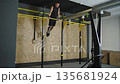 Athlete performs strength training on gym rings in fitness center during afternoon Athlete performs strength training on gym rings in fitness center during afternoon 135681924