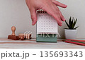 Hand Holding Desk Calendar Displaying May 2027 5 In Minimal Workspace Setting 135693343
