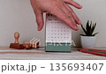 Hand Holding Desk Calendar Showing June 2027 on Office Table With Minimal Workspace Objects 135693407
