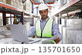 Worker wearing safety vest and helmet working using laptop 135701650