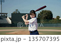 A female baseball player swings the bat vigorously during batting practice and smiles with a sense of accomplishment A female baseball player swings the bat vigorously during batting practice and smiles with a sense of accomplishment 135707395